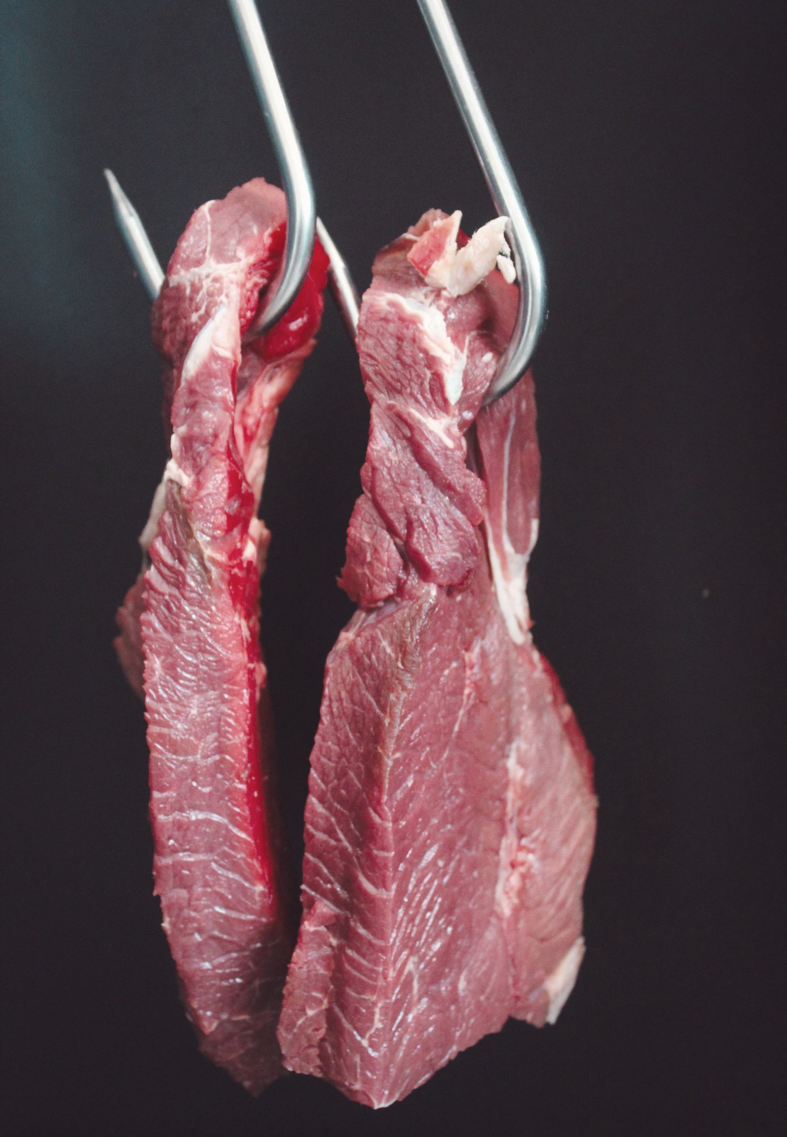 Cuts of beef hanging from butcher’s hooks