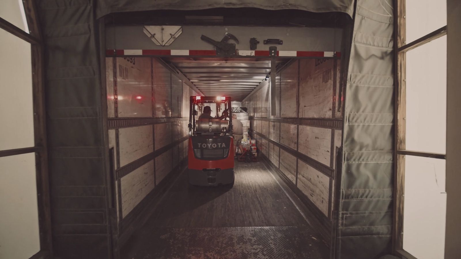 A forklift loading a refrigerated trailer at the depot door